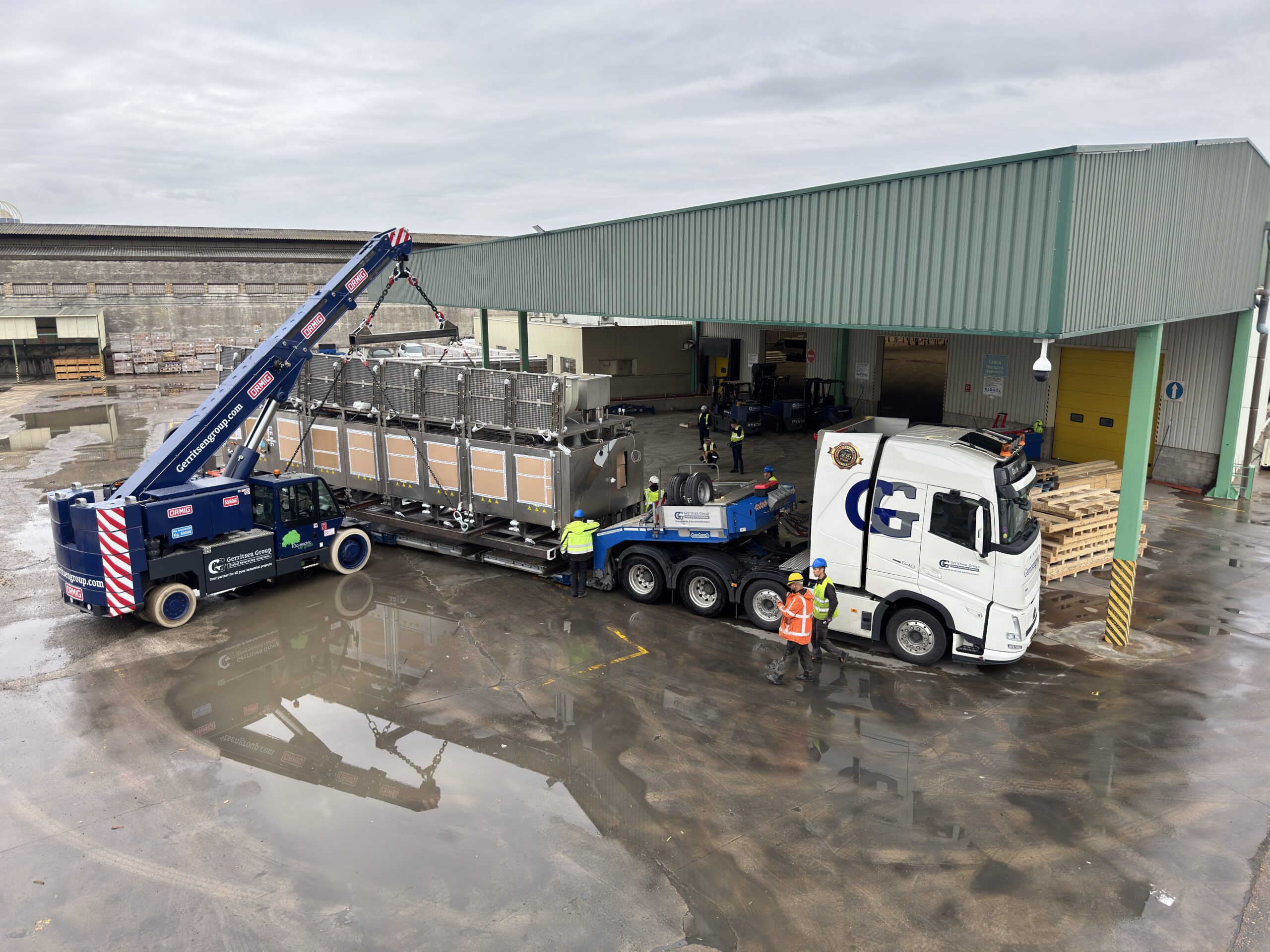 The pick and carry crane lifts a big machine on the trailer of the Gerritsen Group truck. 